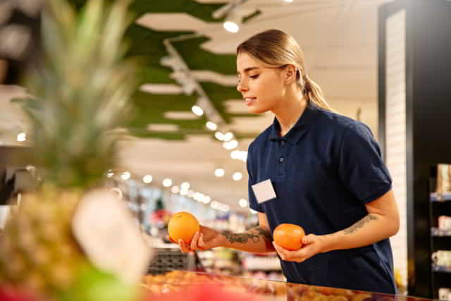 chica reponiendo la sección de fruta en el supermercado