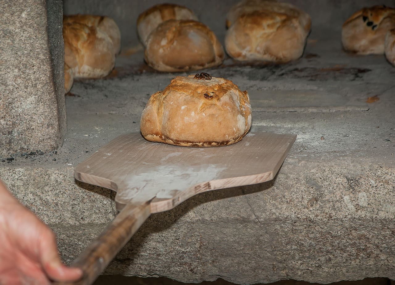 sacando un pan del horno de piedra